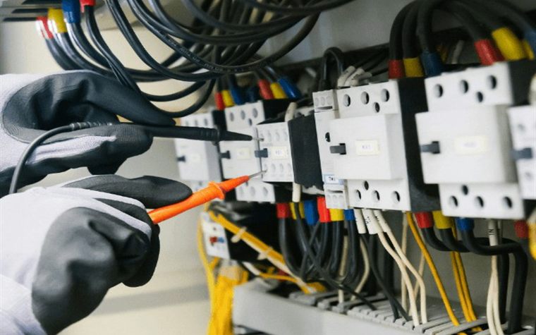Electrician testing an electrical control panel